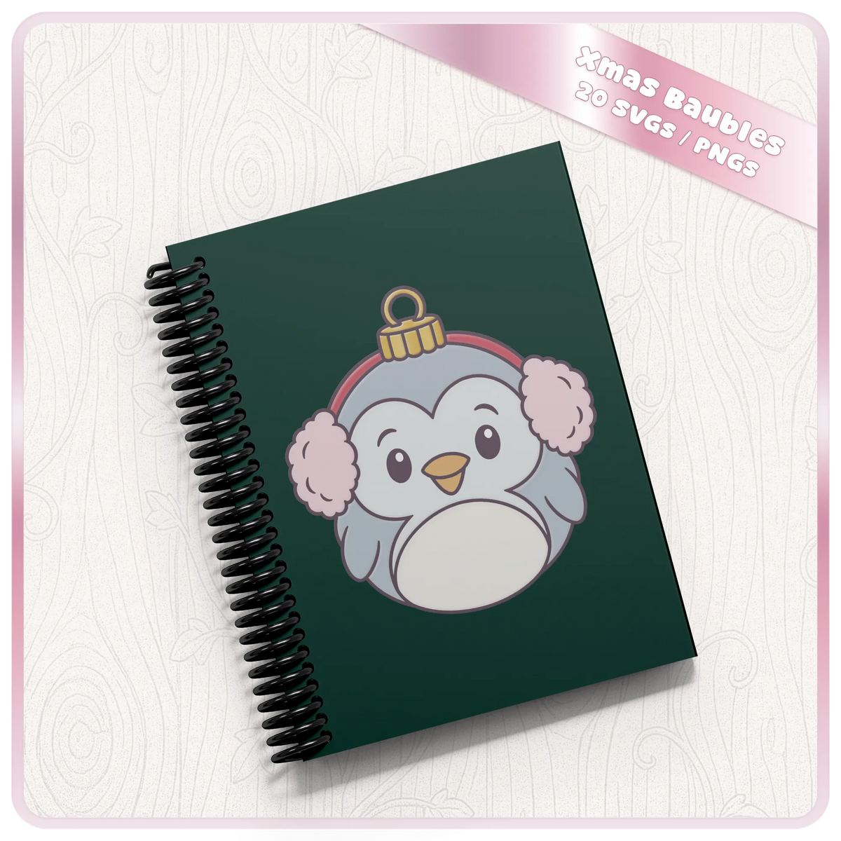Cute Christmas penguin bauble PNG clipart displayed on a green spiral notebook, showing a festive SVG design used for personalised stationery.