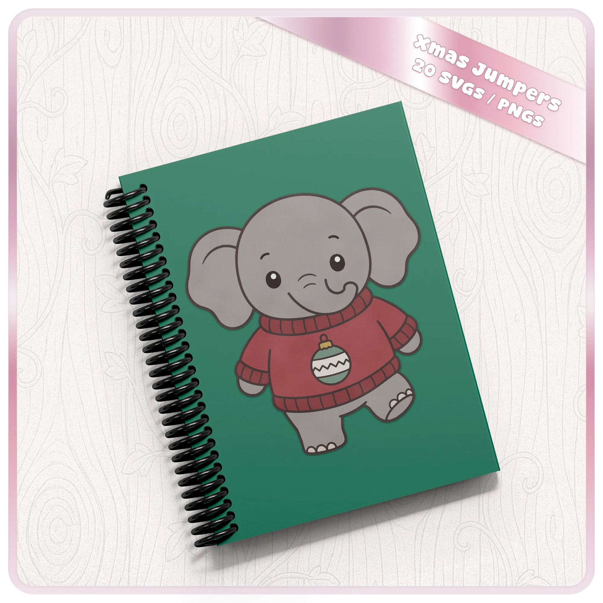 Christmas elephant SVG design displayed on a green spiral notebook mockup, featuring a cute kawaii elephant wearing a red Christmas jumper with festive bauble.